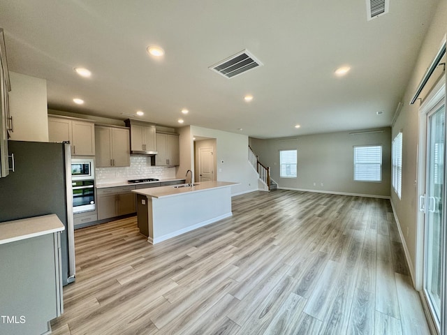 768 Riguard Way, Wendell, NC 27591 - kitchen with appliances with stainless steel finishes, gray cabinetry, a sink, tasteful backsplash, and light wood-style flooring
