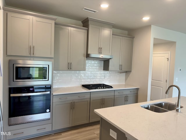 768 Riguard Way, Wendell, NC 27591 - kitchen featuring appliances with stainless steel finishes, a sink, gray cabinets, under cabinet range hood, and decorative backsplash