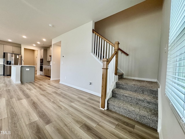 768 Riguard Way, Wendell, NC 27591 - unfurnished living room with recessed lighting, light wood finished floors, baseboards, stairs, and a sink