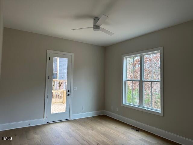 empty room featuring baseboards, wood finished floors, visible vents, and ceiling fan