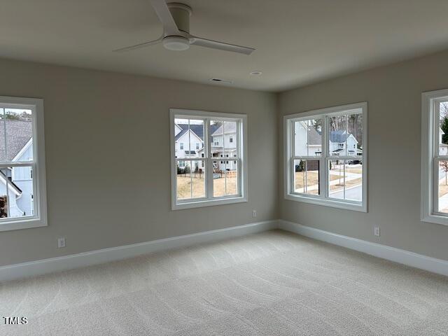 unfurnished room featuring baseboards, light colored carpet, and ceiling fan