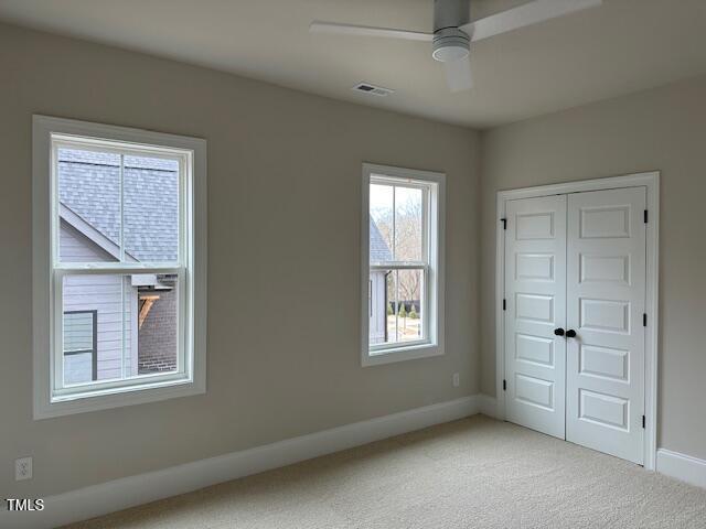 unfurnished bedroom featuring baseboards, visible vents, a closet, and light carpet