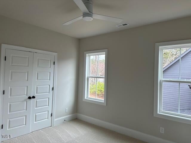 unfurnished bedroom with visible vents, a ceiling fan, a closet, carpet floors, and baseboards