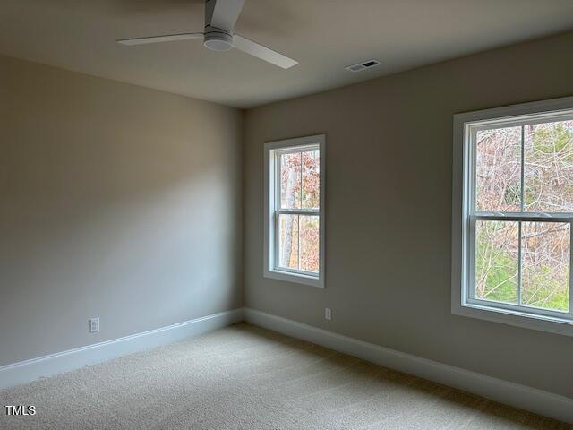 empty room with baseboards, light carpet, visible vents, and a ceiling fan