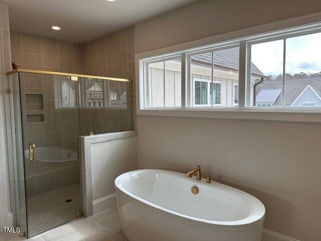 full bathroom featuring tile patterned floors, a healthy amount of sunlight, a stall shower, and a freestanding bath