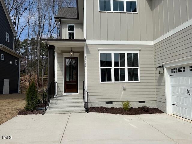 entrance to property with crawl space, a garage, board and batten siding, and roof with shingles