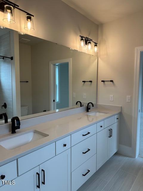 full bathroom with a sink, baseboards, toilet, and double vanity