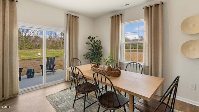 dining area featuring visible vents, baseboards, and wood finished floors