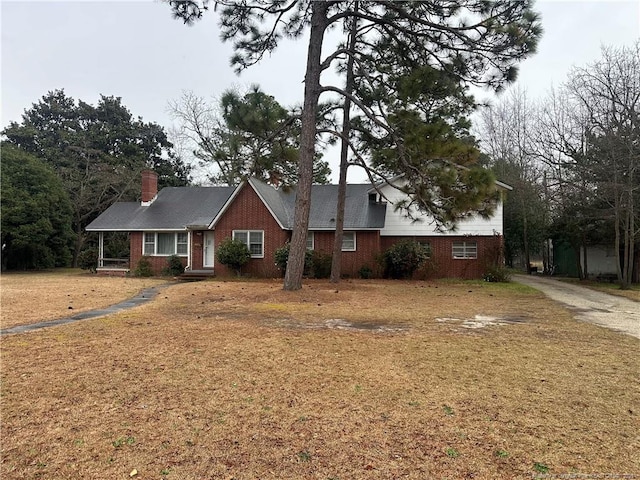 view of front of property with a front yard, brick siding, and a chimney