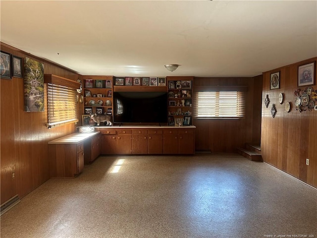 unfurnished living room featuring wooden walls and light floors