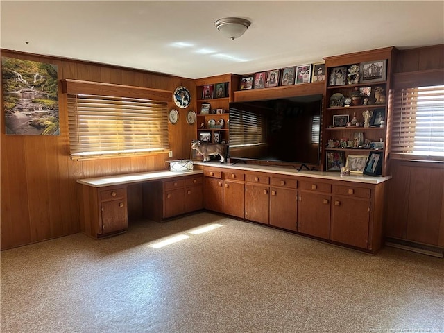 bar featuring light floors, wood walls, and built in desk