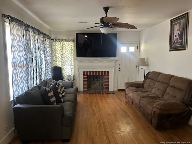 living room featuring wood-type flooring, plenty of natural light, a brick fireplace, and ceiling fan