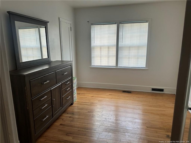 bedroom featuring wood finished floors, visible vents, and baseboards