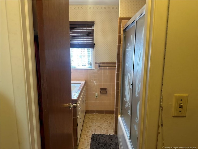 full bathroom with a tub, wallpapered walls, a wainscoted wall, an enclosed shower, and tile walls