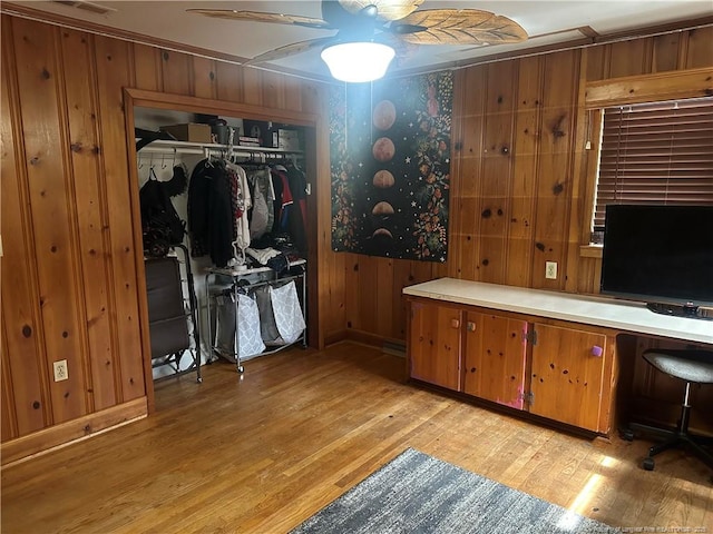 interior space with wooden walls, light wood-style flooring, and ceiling fan