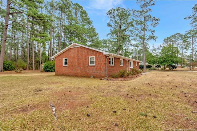 view of side of home featuring brick siding and a yard