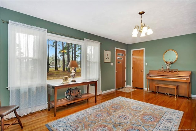 entryway with wood finished floors, a healthy amount of sunlight, baseboards, and a chandelier