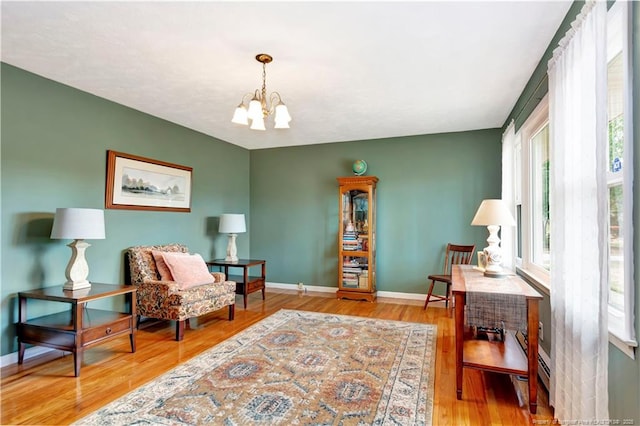 living area with a notable chandelier, baseboards, and wood finished floors