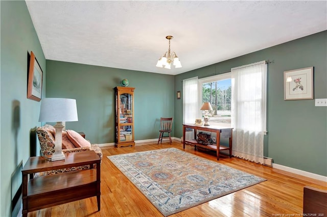 sitting room featuring a notable chandelier, wood finished floors, and baseboards