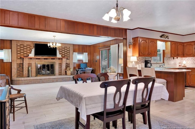 dining area with wooden walls, a notable chandelier, a fireplace, and crown molding