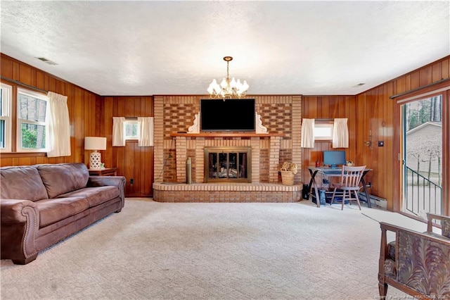 carpeted living room featuring a chandelier, visible vents, a fireplace, and wooden walls