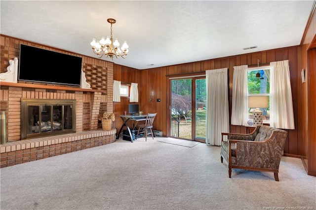 living room with wooden walls, carpet, visible vents, an inviting chandelier, and a fireplace