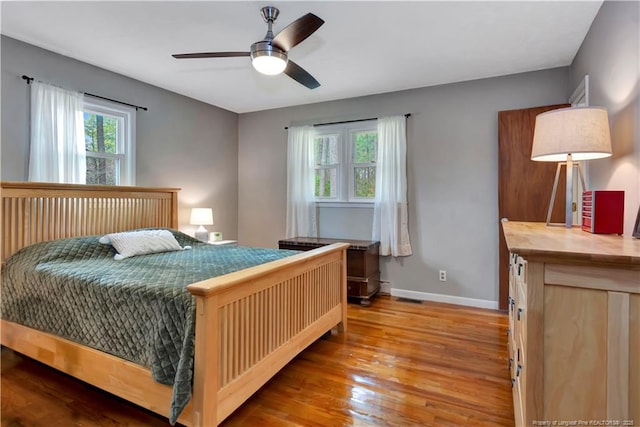 bedroom featuring baseboards, wood finished floors, and a ceiling fan