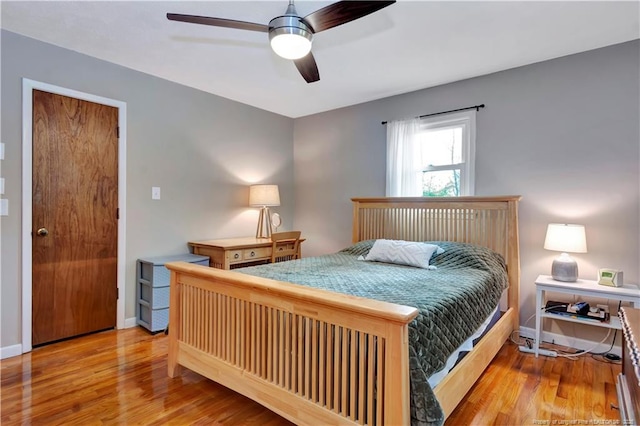 bedroom with a ceiling fan, baseboards, and wood finished floors