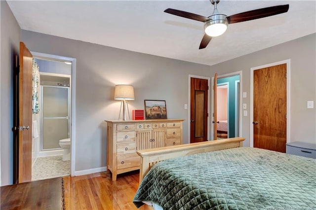 bedroom featuring ceiling fan, baseboards, ensuite bath, and light wood-style flooring