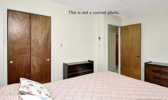 bedroom featuring wallpapered walls and a closet