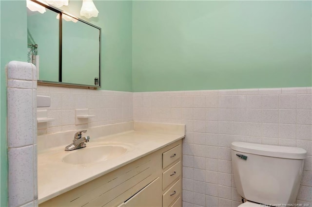 bathroom featuring vanity, tile walls, toilet, and wainscoting