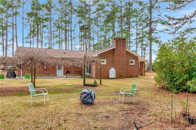 rear view of house with a yard, brick siding, and a chimney