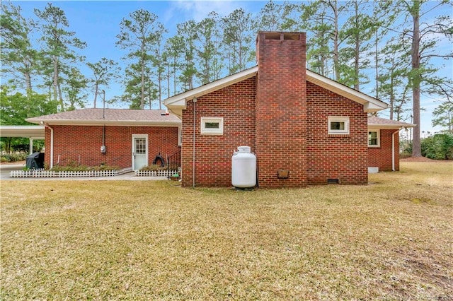 rear view of property with brick siding, crawl space, a chimney, and a yard