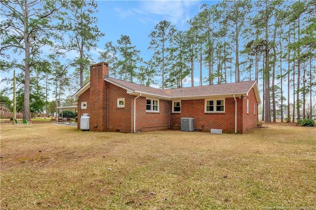 back of house with crawl space, a lawn, cooling unit, and a chimney