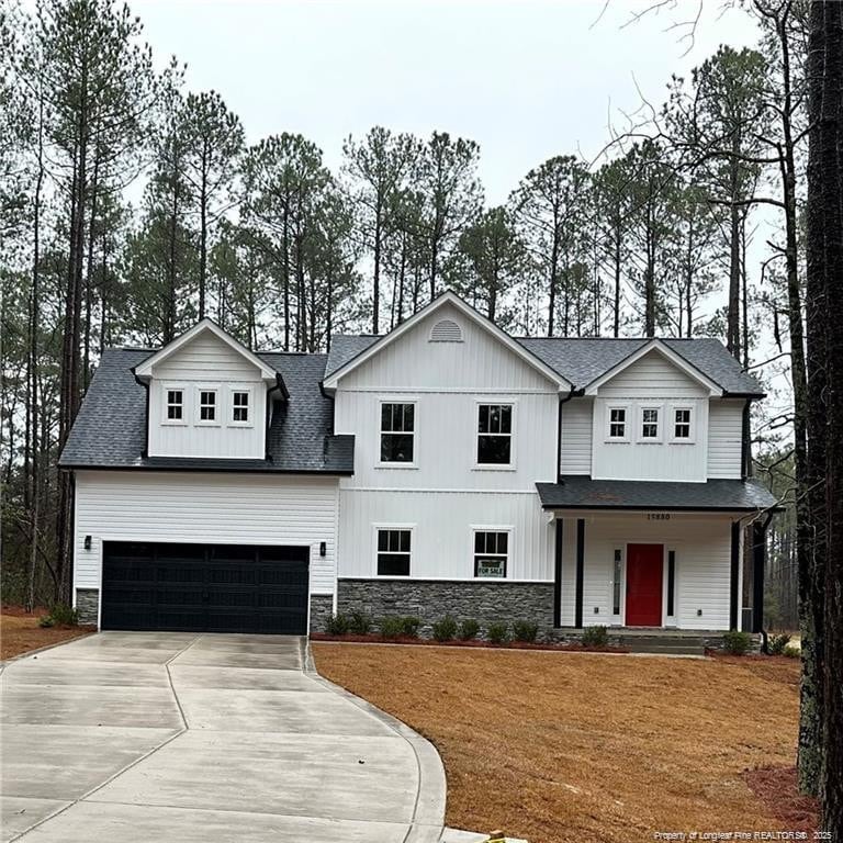 modern inspired farmhouse with an attached garage, stone siding, driveway, and a shingled roof