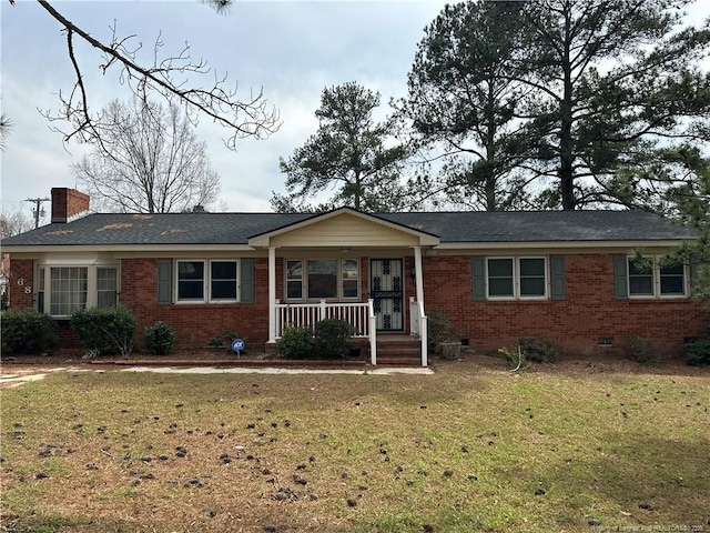 ranch-style home with brick siding, a front yard, covered porch, a chimney, and crawl space