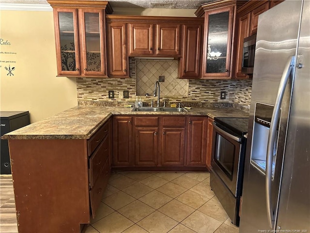 kitchen featuring tasteful backsplash, a peninsula, stainless steel appliances, and a sink