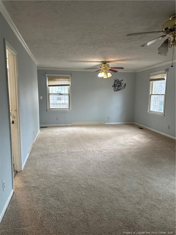 carpeted spare room with visible vents, baseboards, ceiling fan, ornamental molding, and a textured ceiling