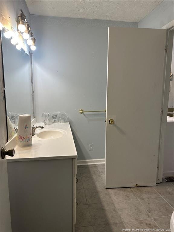 bathroom featuring vanity, baseboards, tile patterned flooring, and a textured ceiling