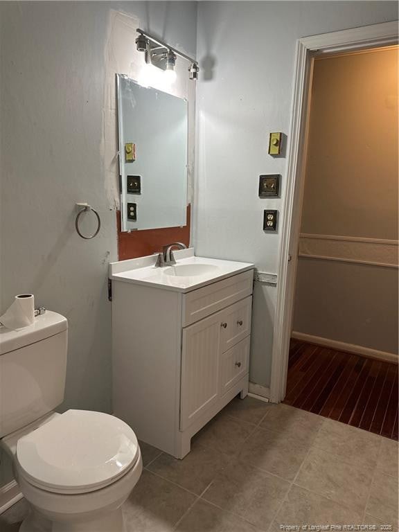 half bathroom featuring tile patterned floors, toilet, and vanity