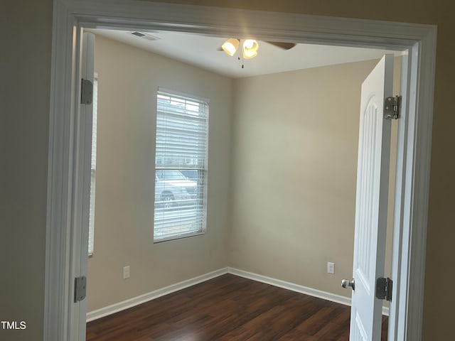 spare room with a wealth of natural light, baseboards, a ceiling fan, and dark wood-style flooring