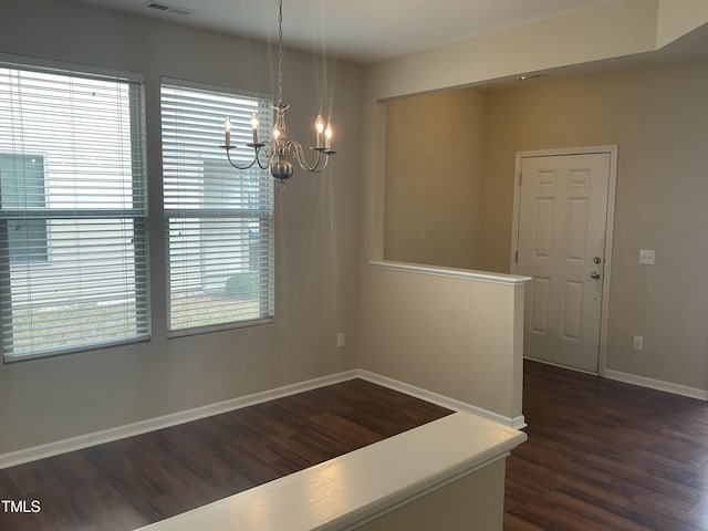 interior space featuring dark wood-type flooring, a notable chandelier, baseboards, and a wealth of natural light