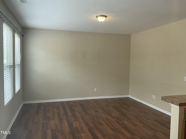 empty room featuring dark wood-style floors and baseboards