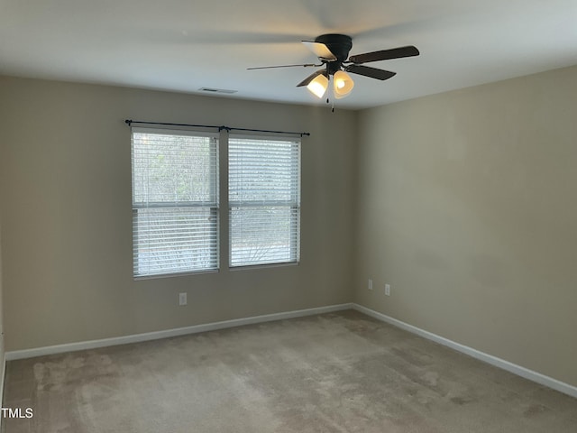 spare room with visible vents, light colored carpet, baseboards, and ceiling fan