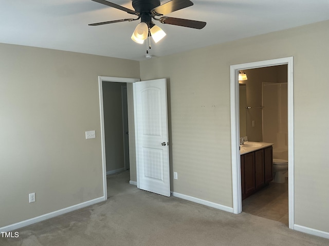 unfurnished bedroom with a ceiling fan, baseboards, a sink, ensuite bathroom, and light colored carpet