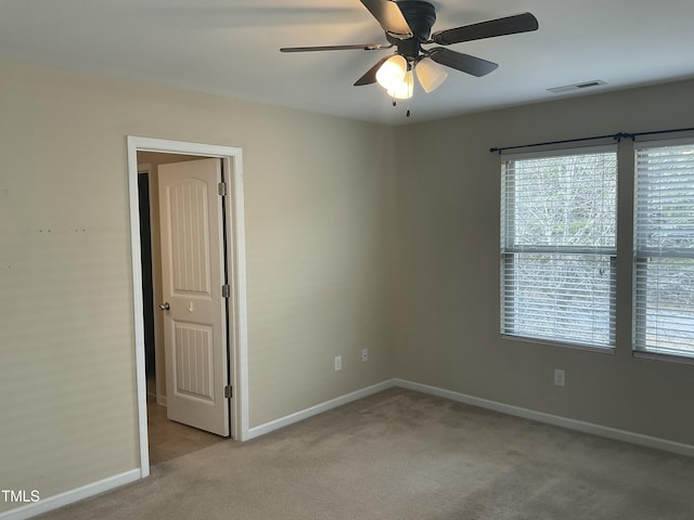 carpeted empty room with baseboards, visible vents, and ceiling fan