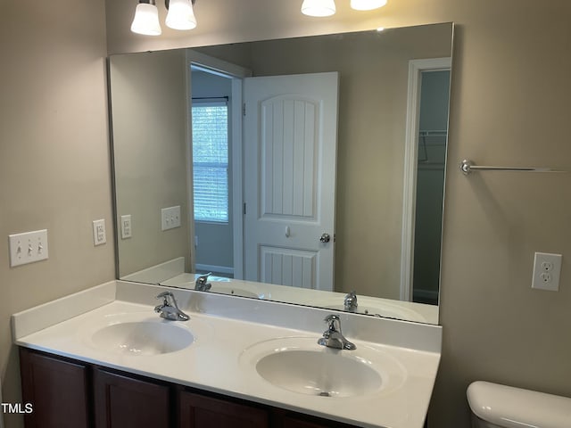 bathroom featuring a sink, toilet, and double vanity