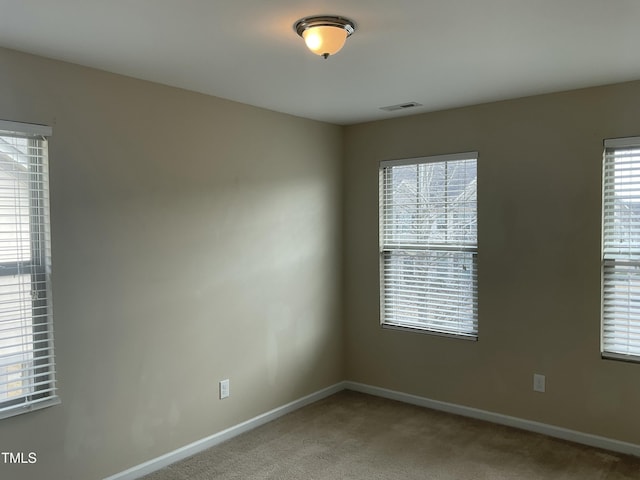 carpeted empty room with visible vents, plenty of natural light, and baseboards