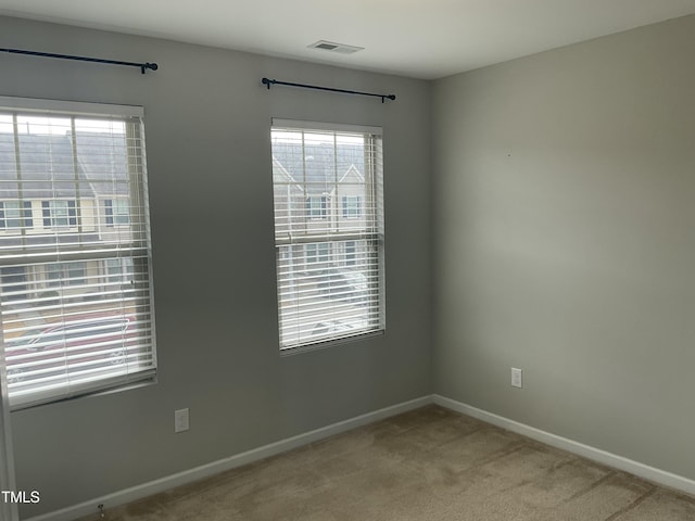 empty room featuring carpet flooring, baseboards, and visible vents