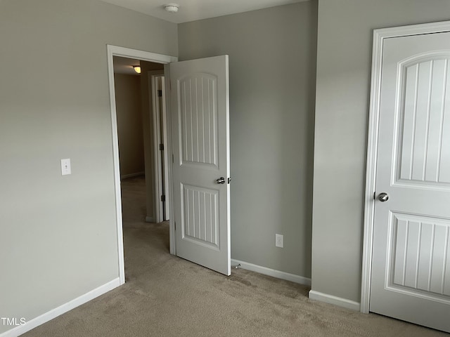 unfurnished bedroom with baseboards and light carpet